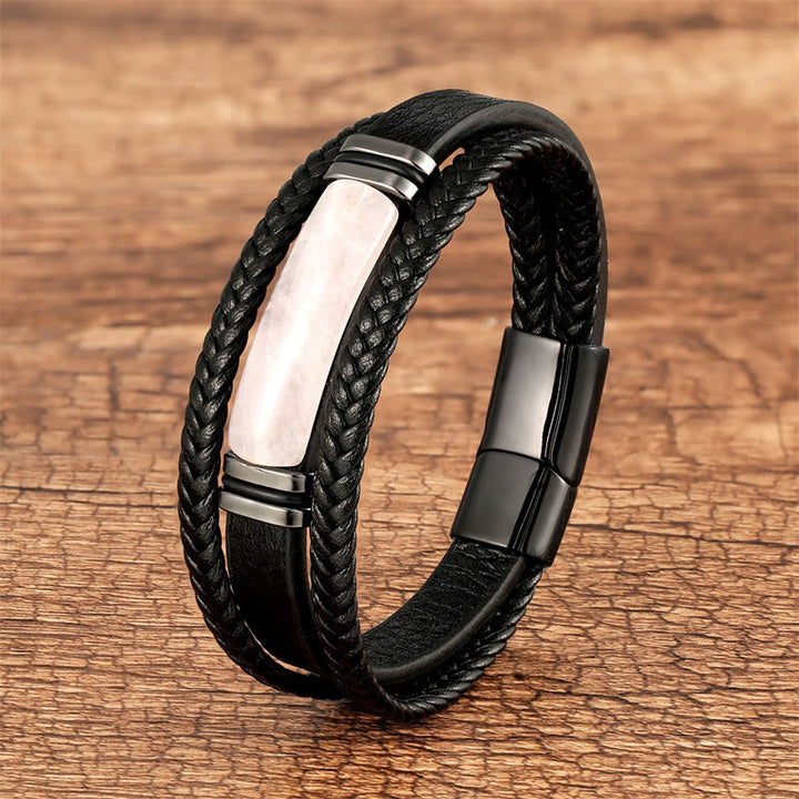Schwarzes Leder Armband mit Perlmutt Stein auf Holzuntergrund.