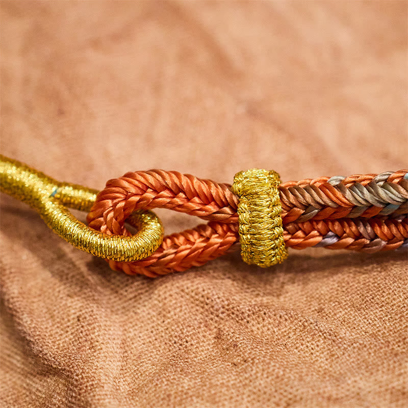 Geflochtenes Armband mit Friedensknoten in Gold und Orange Nahaufnahme