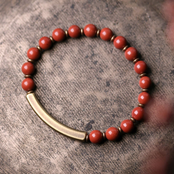 Rotes Achat Armband mit goldenem Röhrchen auf grauem Untergrund Nahaufnahme