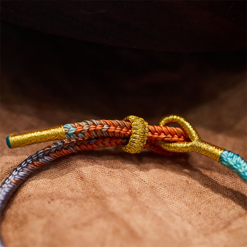 Geflöchtenes Armband mit Friedensknoten in Gold, Rot und Türkis Nahaufnahme