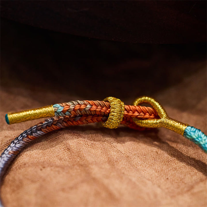 Geflöchtenes Armband mit Friedensknoten in Gold, Rot und Türkis Nahaufnahme