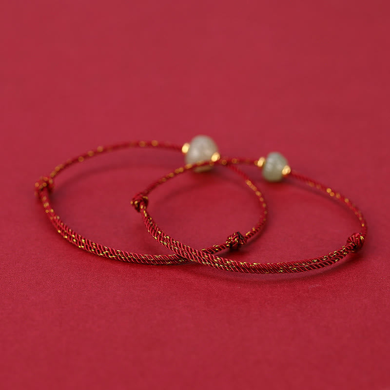 Zwei goldene Armbänder mit Perlen auf rosa Hintergrund elegant.