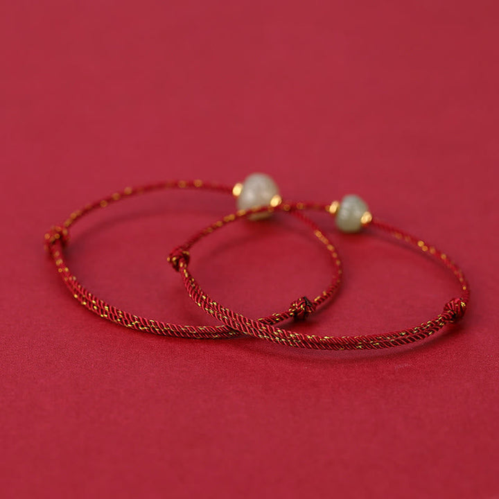 Zwei goldene Armbänder mit Perlen auf rosa Hintergrund elegant.