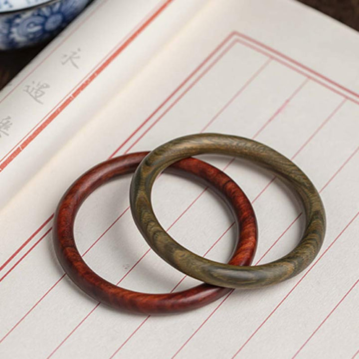 Zwei Sandelholz Armbänder auf Notizbuch Flachlage Rot Braun Naturholz