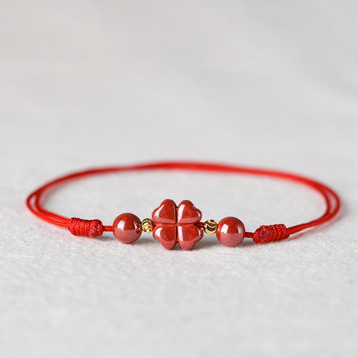 Rotes Armband Zinnober Kleeblatt mit Natursteinen auf weißem Hintergrund Nahaufnahme