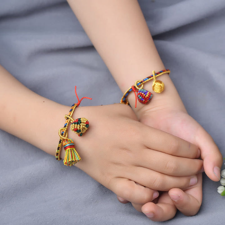 Buntes Armband mit Zongzi-Charm am Kinderhandgelenk, golden glänzend.