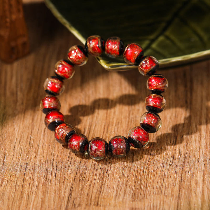 Rotes Perlenarmband mit Glückssteinen auf Holzuntergrund elegant.