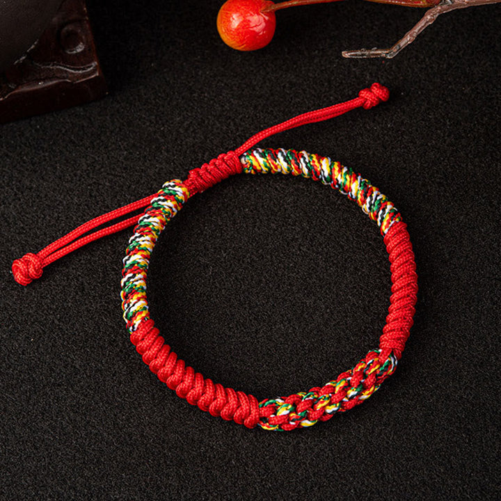 Rotes Mala-Armband mit bunten Perlen auf dunklem Hintergrund Flachlage