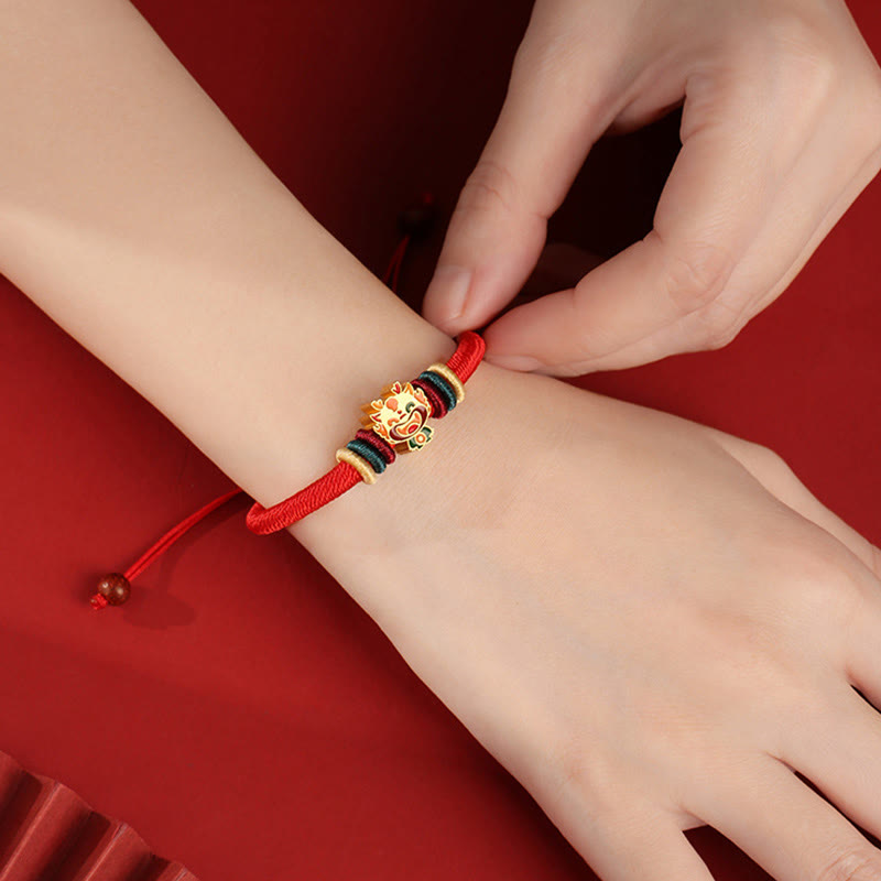 Rotes Armband mit goldenem Tierkreis-Charm elastisch getragen.