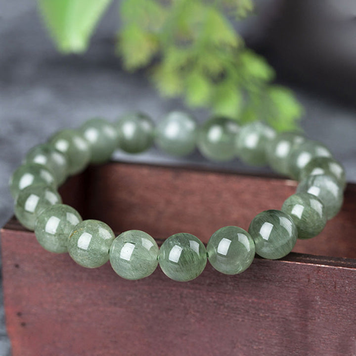 Grünes Kristall Armband Armreif Naturstein Perlen auf Holzoberfläche Wohlstand Segen