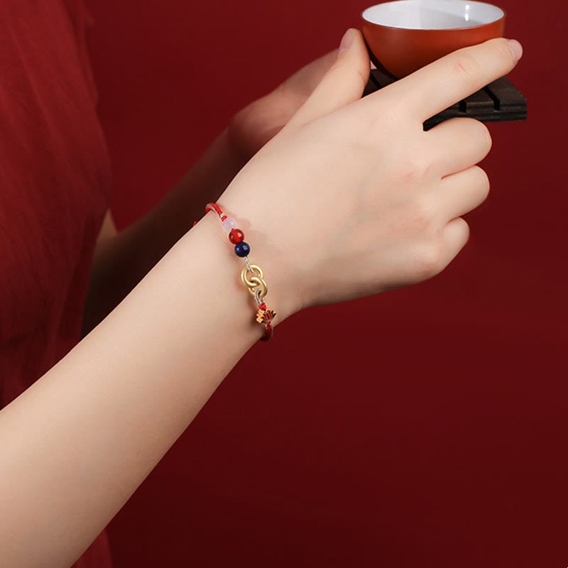 Rotes Armband mit Lotus-Anhänger am Handgelenk elegant präsentiert
