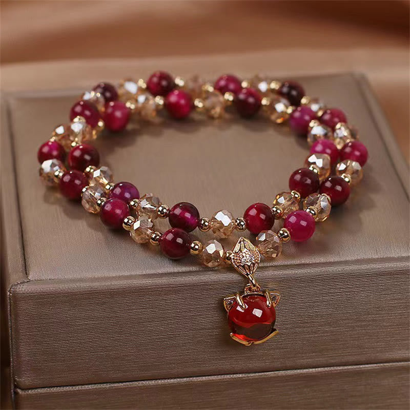 Rotes Armband mit Perlen und goldenem Anhänger auf Schmuckbox.