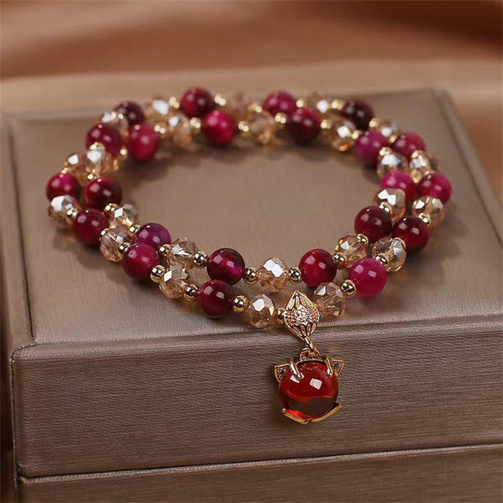 Rotes Armband mit Perlen und goldenem Anhänger auf Schmuckbox.