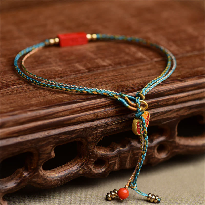 Armband Zinnober – Segen & Balance, blau-goldenes Geflecht mit roten Perlen