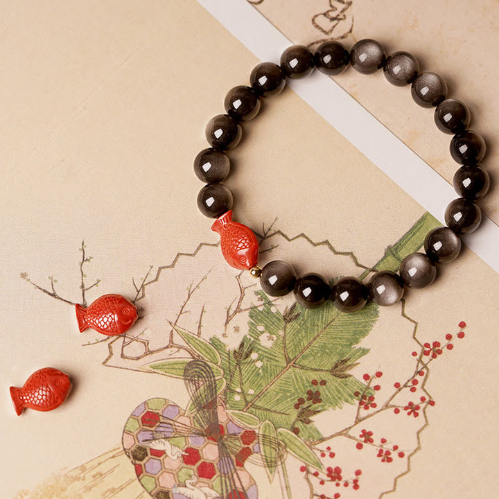 Obsidian Armband mit roten Koi Fischen Perlen auf Beige Hintergrund