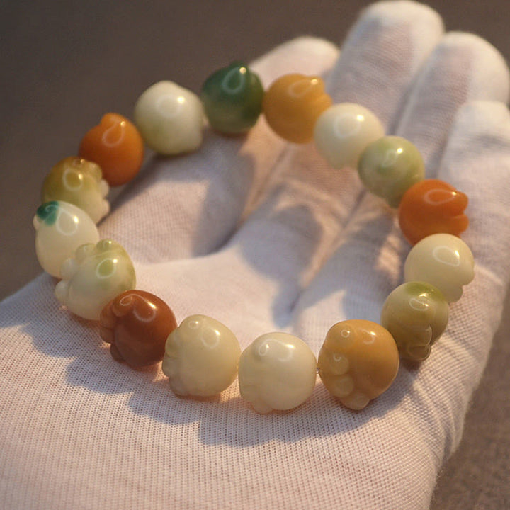 Bodhi-Armband mit Natursteinen in Creme, Orange und Grün Tönen.