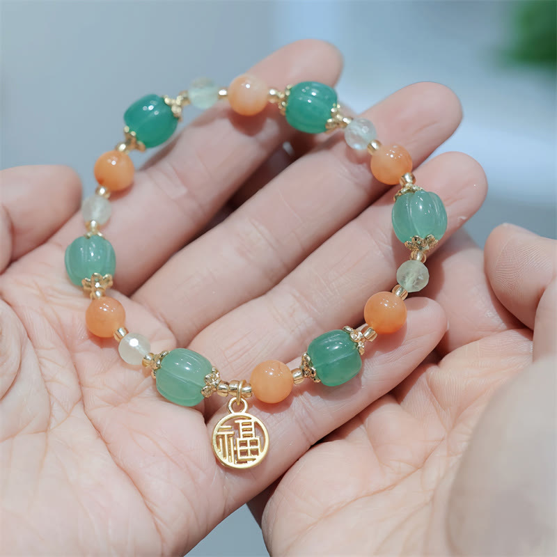 Jade Armband mit Fu-Zeichen Anhänger in Grün und Orange Tönen.