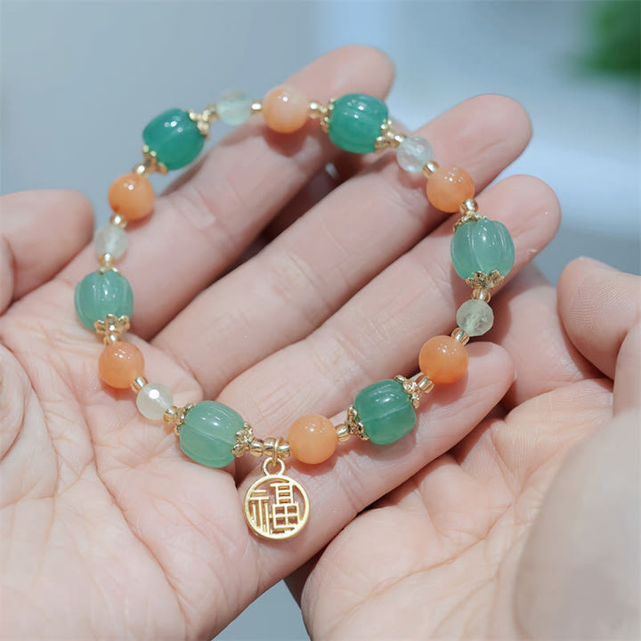 Jade Armband mit Fu-Zeichen Anhänger in Grün und Orange Tönen.