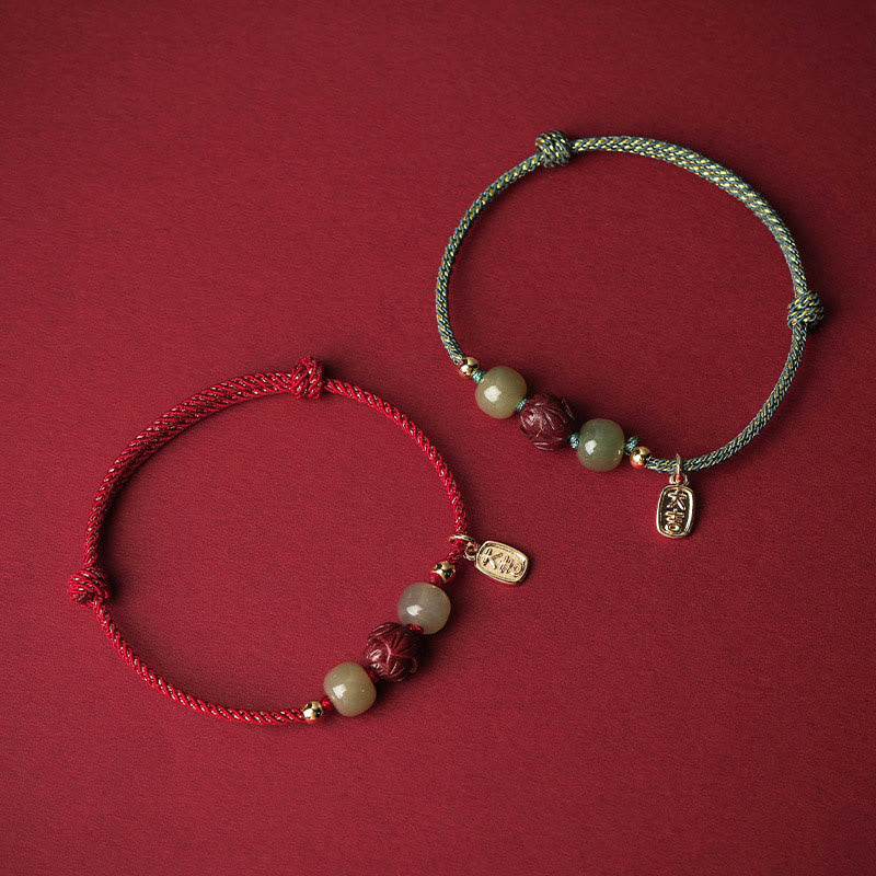 Zwei Armbänder mit Jade, Lotus und Zinnober auf rotem Hintergrund.