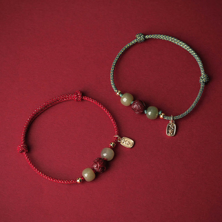 Zwei Armbänder mit Jade, Lotus und Zinnober auf rotem Hintergrund.