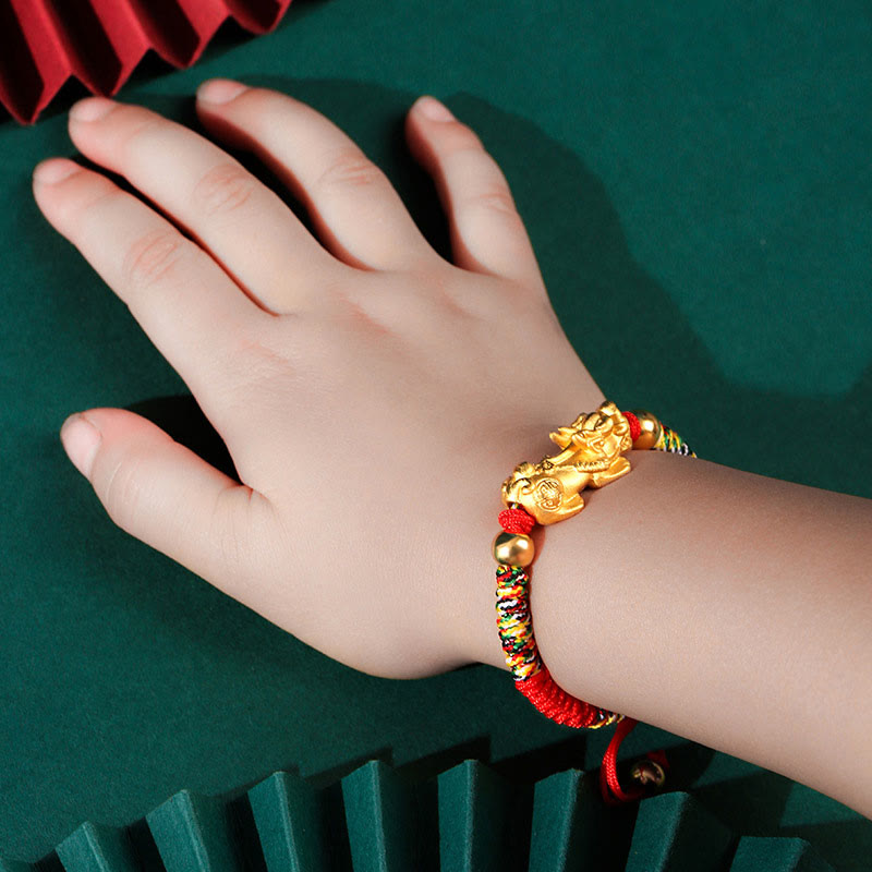 Vergoldetes Pixiu Armband mit roten Perlen am Handgelenk getragen.