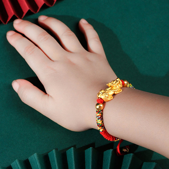 Vergoldetes Pixiu Armband mit roten Perlen am Handgelenk getragen.