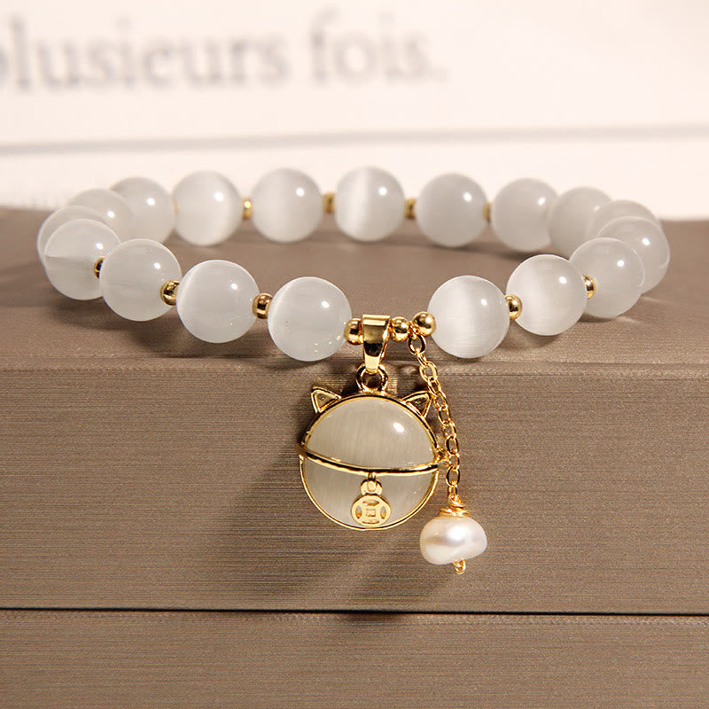Weißes Perlen Armband mit goldener Katze Anhänger auf Holz Oberfläche