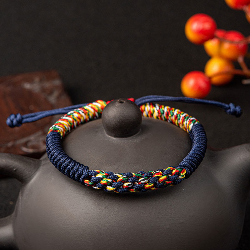 Bunte Mala Armband auf grauer Teekanne mit Herbstbeeren Dekoration.