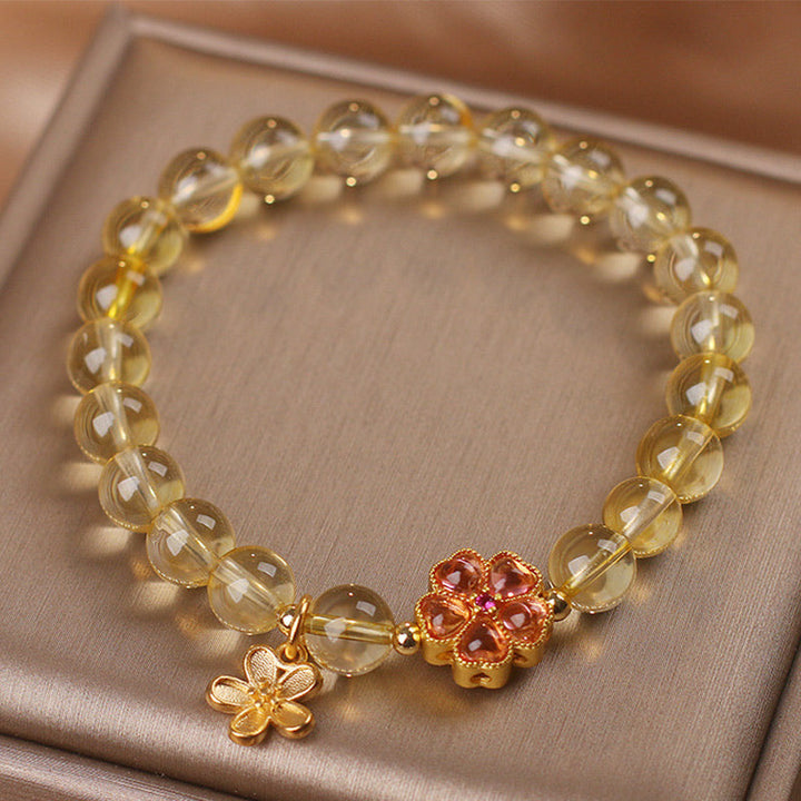 Armband Citrin mit goldenen Blüten-Charms am Handgelenk getragen