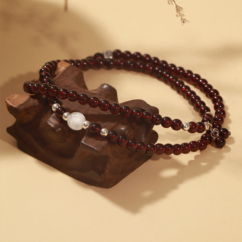 Granat Armband mit Silber und weißem Stein auf Holzständer.