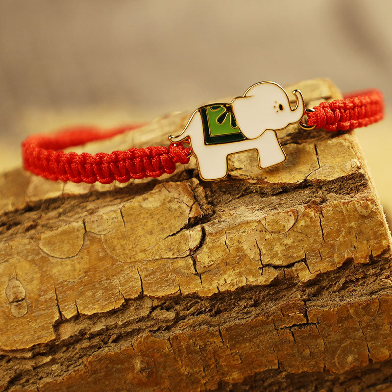 Rotes Armband mit silbernem Elefant Charm auf Holz.