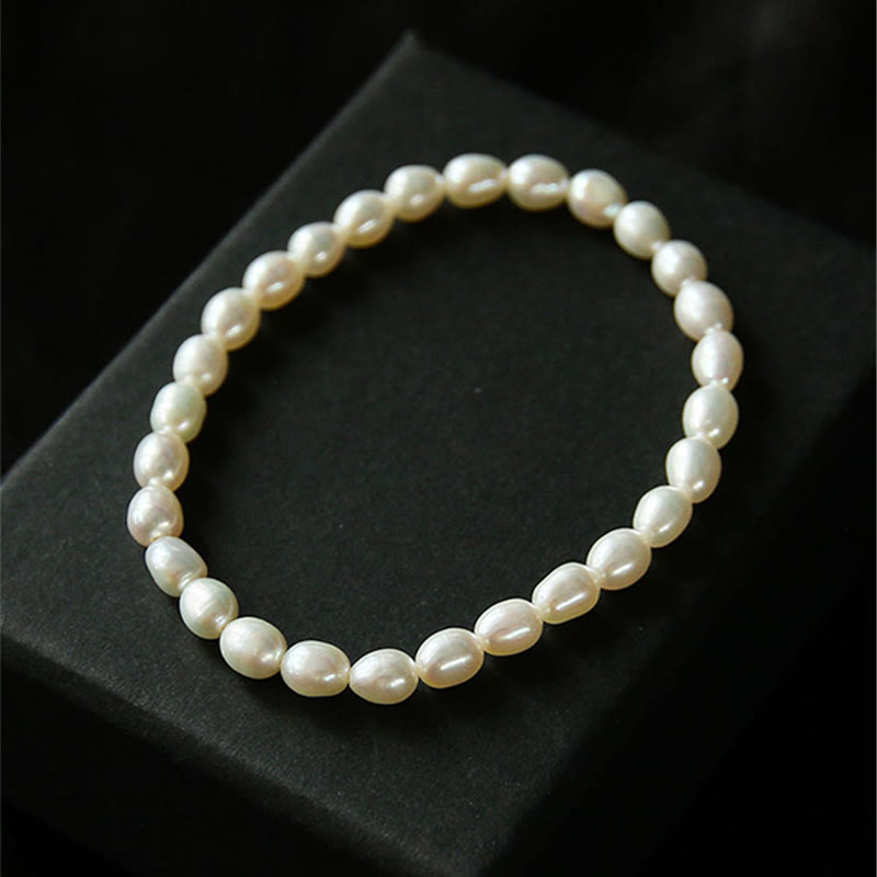 Armband Perle – Heilung mit cremefarbenen Perlen auf schwarzem Hintergrund
