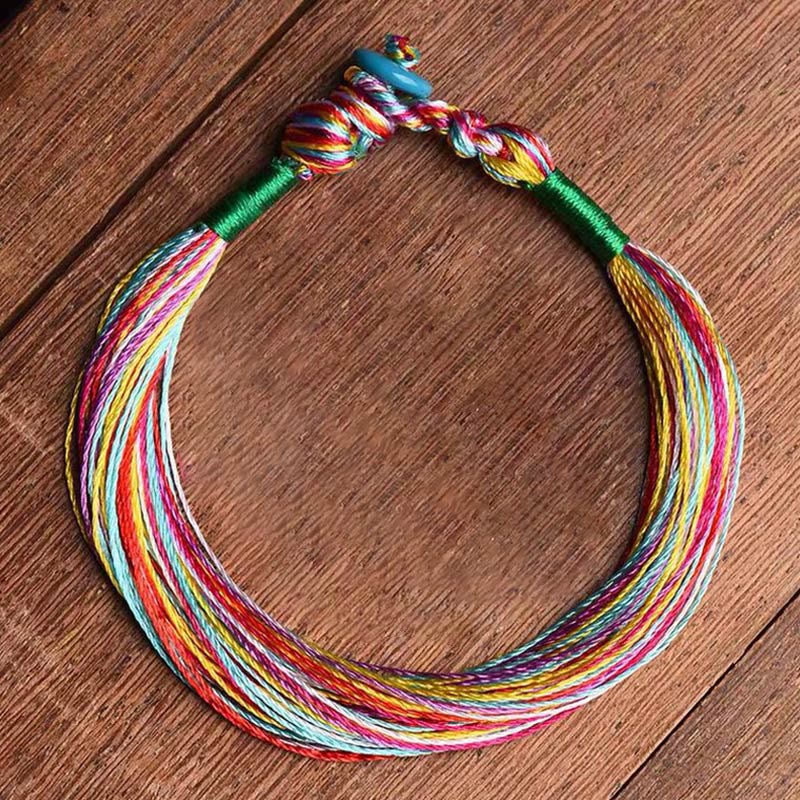 Buntes Fünffarben Armband mit Schutzenergie auf Holzuntergrund.