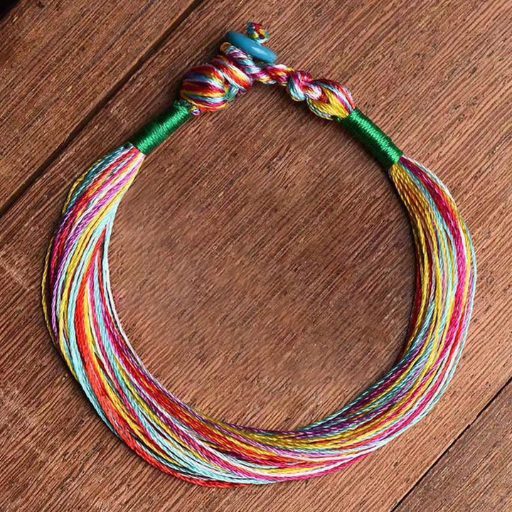 Buntes Fünffarben Armband mit Schutzenergie auf Holzuntergrund.