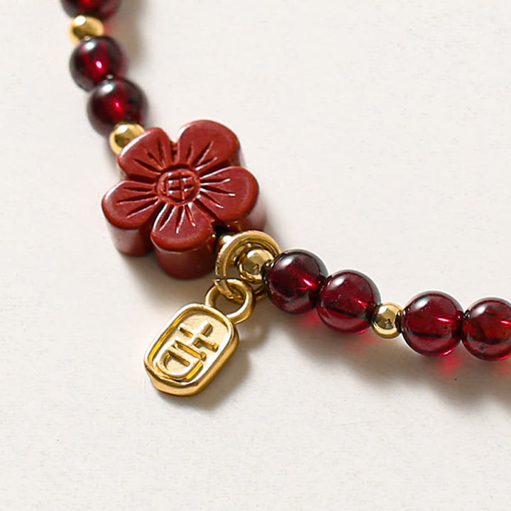 Armband mit roter Blume, Granat Perlen und goldenem Anhänger Flachansicht.