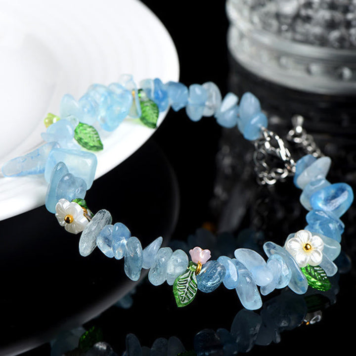 Armband Erdbeerquarz Aquamarin mit Blüten und Blättern dekoriert am Handgelenk