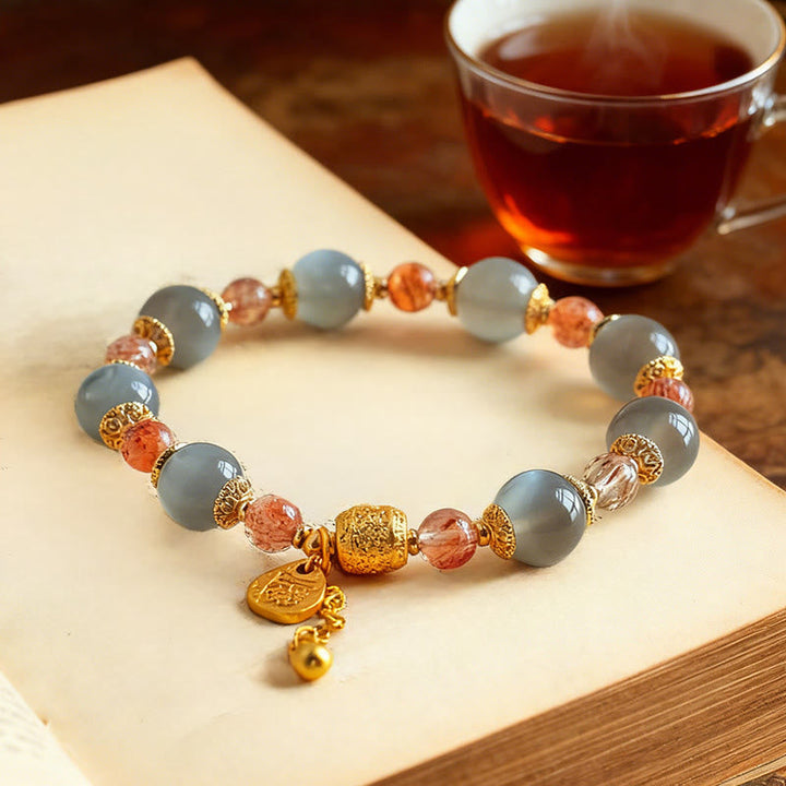 Armband Erdbeerquarz Mondstein Mond Heilung Positivität auf Buch mit Tee