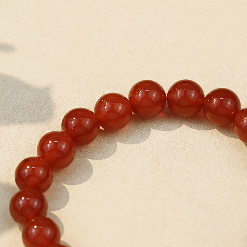 Armband Roter Achat – Erfolg, glänzende rote Perlen auf hellem Untergrund