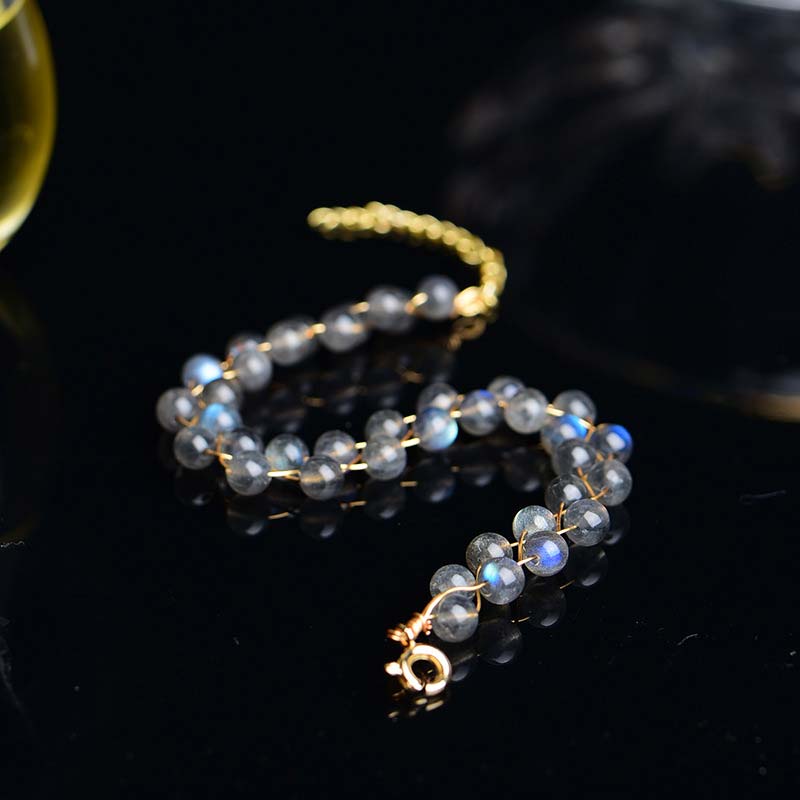 Mondstein Armband mit goldenem Verschluss, facettierte graue Perlen, Detailaufnahme auf schwarzem Hintergrund