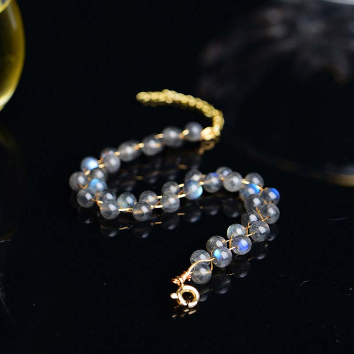 Mondstein Armband mit goldenem Verschluss, facettierte graue Perlen, Detailaufnahme auf schwarzem Hintergrund