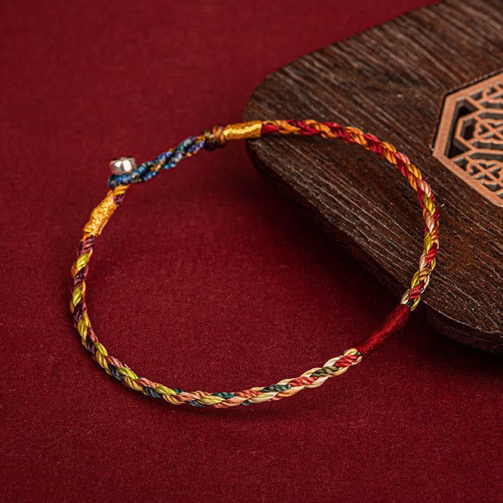 Buntes geflochtenes Armband mit Glücksfaden auf rotem Hintergrund Flat Lay