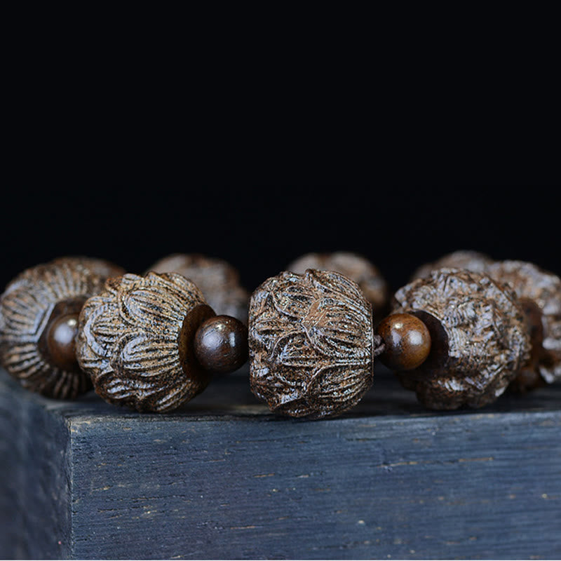 Ebenholz Drachen Armband mit braunen Holzperlen auf Holzoberfläche.