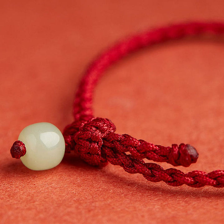 Armband Jade Lotus mit weißer Kugel rote Schnur Nahaufnahme Wohlstand Frieden