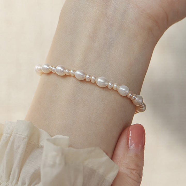 Elegantes Perlenarmband mit weißen Perlen am Handgelenk getragen.