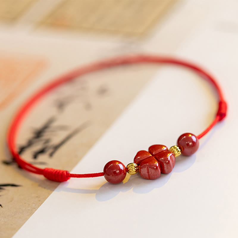 Rotes Armband mit Zinnober-Perlen und goldenen Zwischenteilen auf Papier