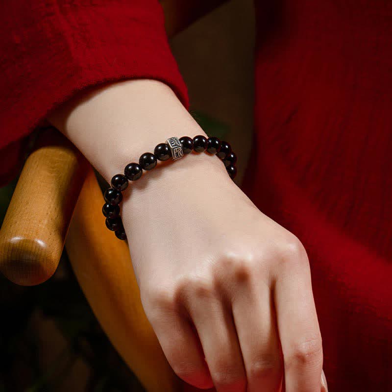 Schwarzes Obsidian Armband mit Silber Charm am Handgelenk getragen elegant