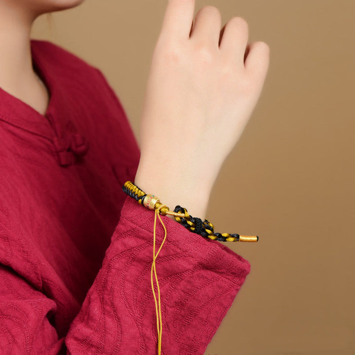 Armband Om Mani Padme Hum Gold schwarz gelb geflochten Handgelenk getragen