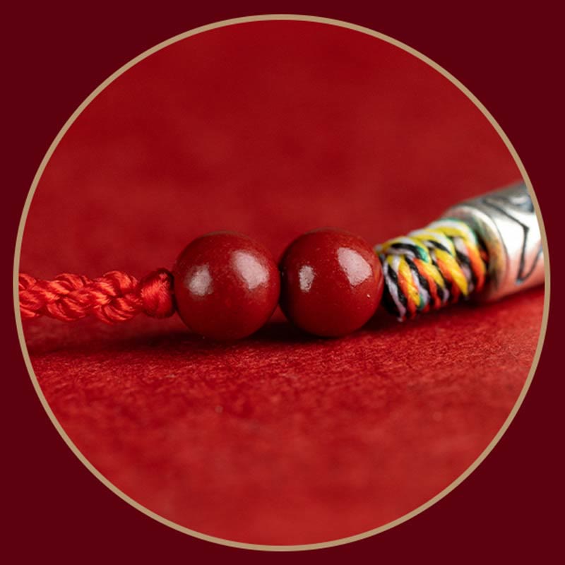Rotes Armband mit Kugeln und Seildetail auf rotem Hintergrund.