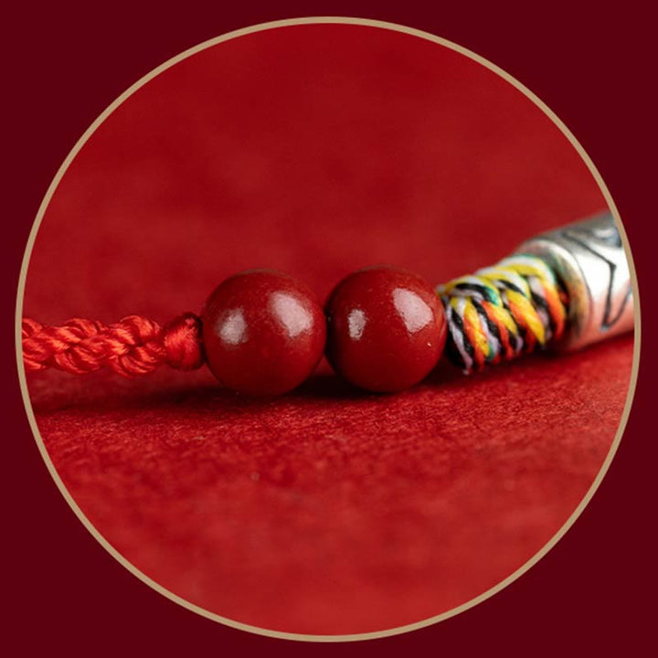 Rotes Armband mit Kugeln und Seildetail auf rotem Hintergrund.