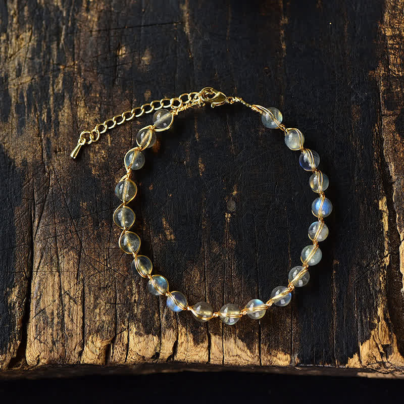 Mondstein Armband mit goldenen Kettendetails auf Holzoberfläche Nahaufnahme